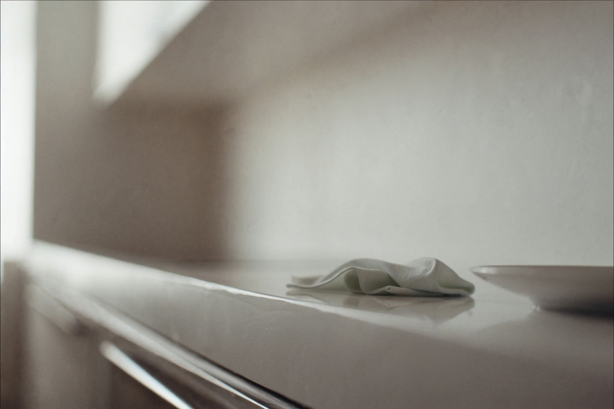 Spotless kitchen countertop with a folded cloth and a ceramic dish, soft daylight